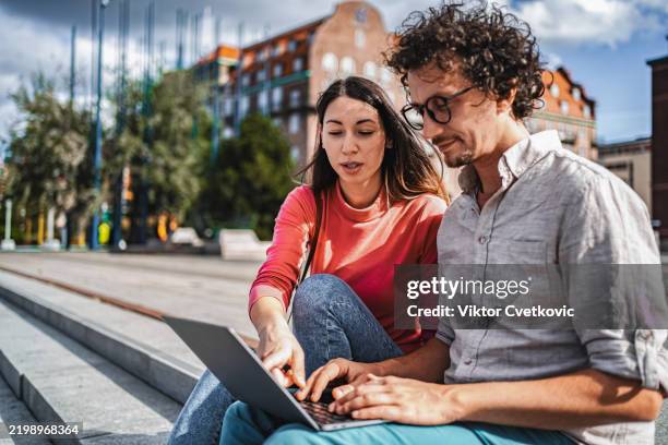 young colleagues working on a laptop in malmo, sweden - internet surfen stockfoto's en -beelden
