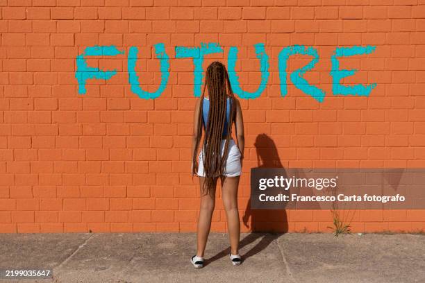 rear view of a woman looking at the word future written on a wall - rivoluzione foto e immagini stock