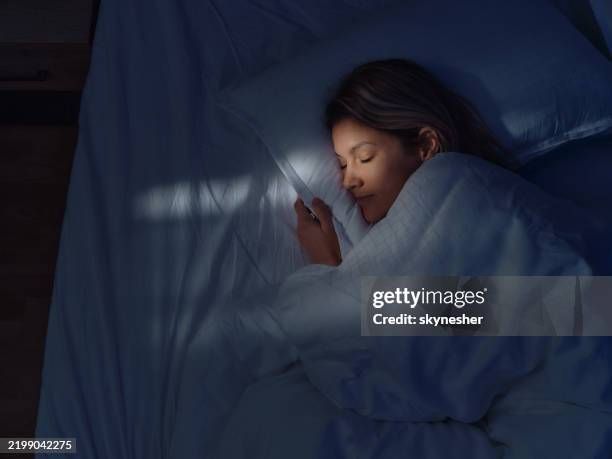above view of relaxed woman sleeping in bed at night. - slapen stockfoto's en -beelden