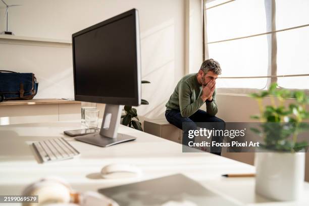 professional businessman covering face with hands, showing workplace exhaustion and mental strain - resolve conflict stock pictures, royalty-free photos & images