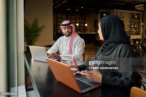empresarios que usan computadoras portátiles una al lado de la otra en la oficina de riyadh - árabes fotografías e imágenes de stock