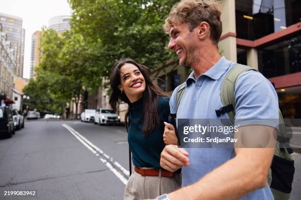 happy young couple exploring urban streets on a sunny day - couple crossing street stock pictures, royalty-free photos & images