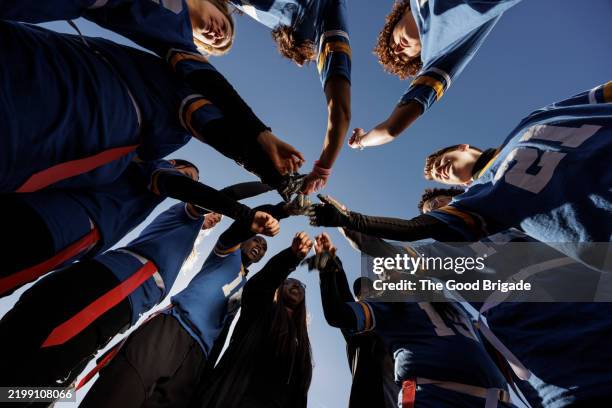 directly below view of coach and players gathered in circle with hands together before flag football game - köpfe zusammenstecken stock-fotos und bilder