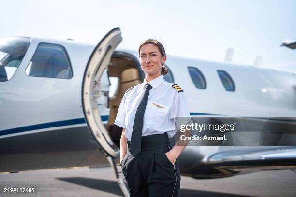 confident female pilot by private jet - piloting stock pictures, royalty-free photos & images