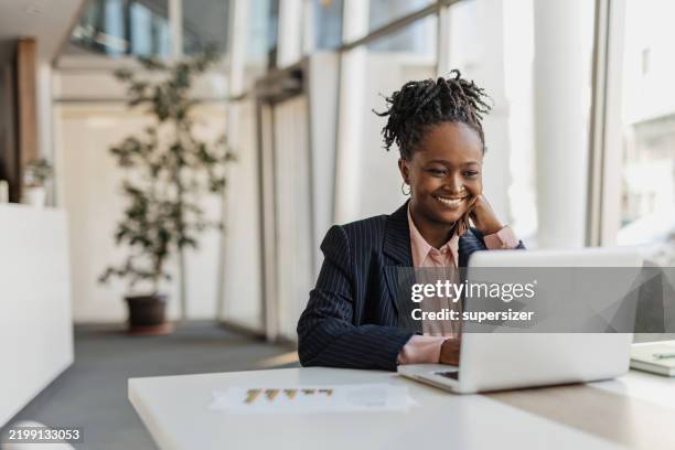 mujer de negocios sonriendo mientras trabaja en su computadora portátil - usar el ordenador fotografías e imágenes de stock