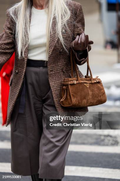 Guest wears brown suede Prada bag outside Michael Kors during New York Fashion Week on February 11, 2025 in New York City.