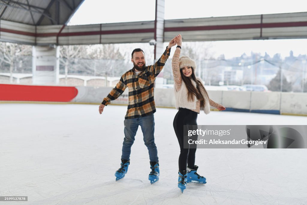 Joyful Couple Spinning and Dancing While Ice Skating on Ice Rink