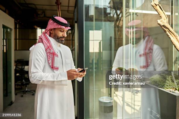 un homme d’affaires de riyad utilise le téléphone dans un bureau moderne - culture saoudienne photos et images de collection