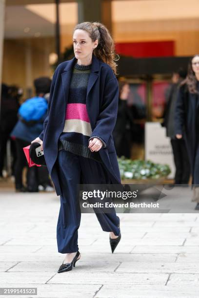 Guest wears gold earrings, navy blue oversized wool coat, dark gray bright pink white pattern oversized sweater, navy blue loose trouser pants, shiny...
