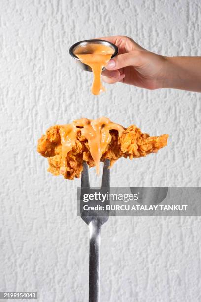 sauce pouring over one piece of chicken tenders - spicy chicken tenders stock pictures, royalty-free photos & images