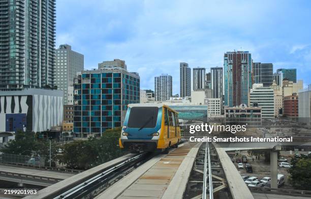 miami "metromover" skytrain, an elevated people mover "transit system" in miami with miami skyline in the background in miami, florida, usa - elevated train stock pictures, royalty-free photos & images