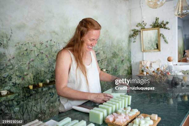 mujer cortando trozos de jabón orgánico hecho a mano en su tienda - condición natural fotografías e imágenes de stock