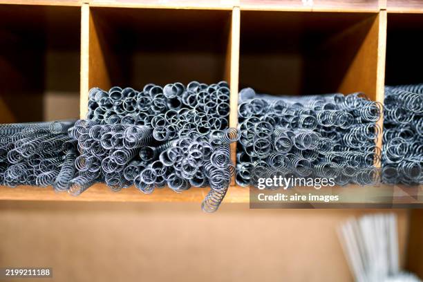 metal springs stacked on wooden shelves in a workshop - spare book stock pictures, royalty-free photos & images