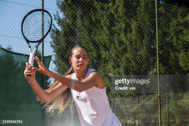 determined caucasian female tennis player in action outdoors - forehand stock pictures, royalty-free photos & images