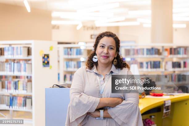 confident latina librarian in a modern library - librarian stock pictures, royalty-free photos & images