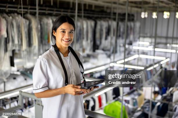 happy woman working at a laundromat using a digital tablet - dry cleaners stock pictures, royalty-free photos & images