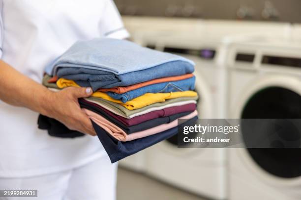 close-up on a maid holding folded clothes at a laundromat - laundry stock pictures, royalty-free photos & images