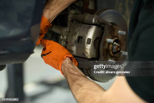 mechanic repairing car brake system in workshop - brake pad stock pictures, royalty-free photos & images