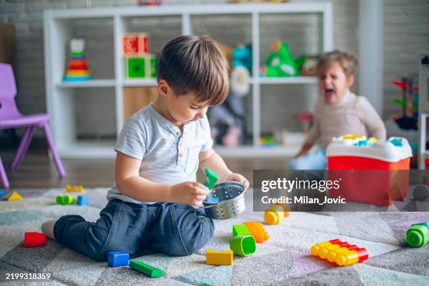 a little boy makes a mess with his toys while a little girl cries - brother and sister crying stock pictures, royalty-free photos & images