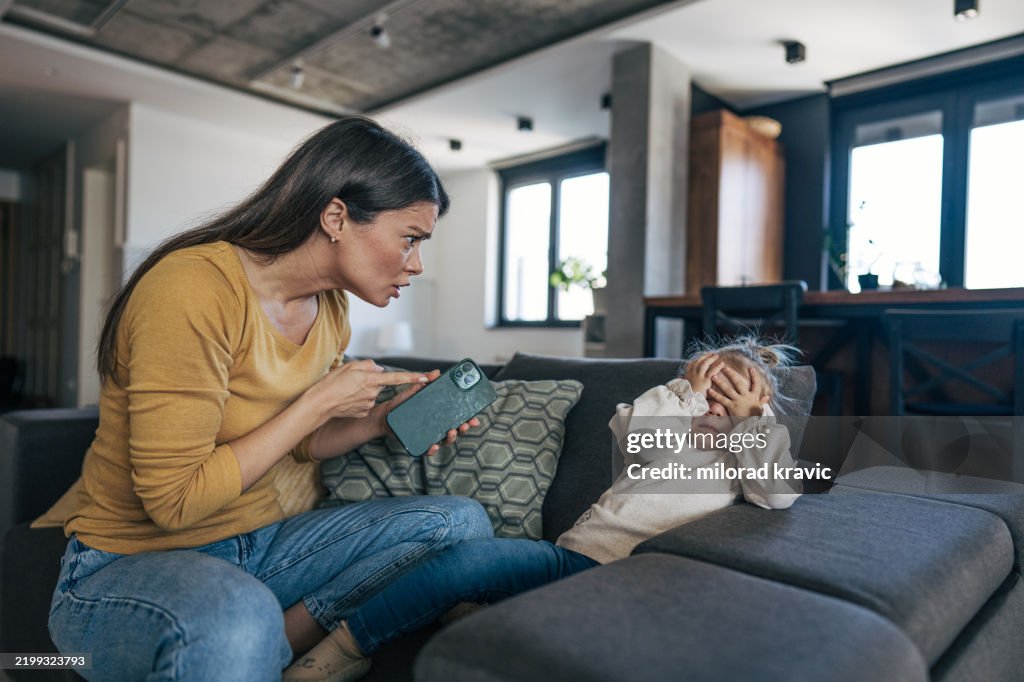 Mother scolding little daughter for breaking her smartphone