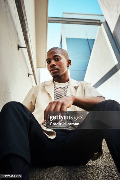 jeune homme élégant assis sur un escalier urbain par une journée ensoleillée - représentation masculine photos et images de collection