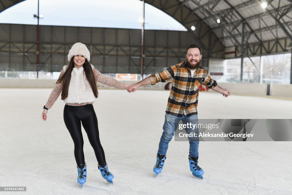 Boyfriend and Girlfriend Holding Hands While Ice Skating Helping Each Other With Balance
