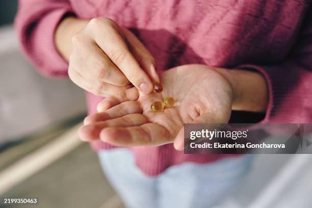 close-up of a person holding vitamin capsules in natural lighting - omega 3 stock pictures, royalty-free photos & images