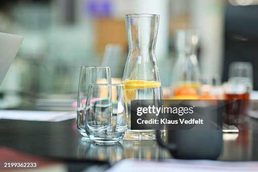 Fresh lemon water in pitcher with drinking glass Fresh lemon water in pitcher with drinking glass