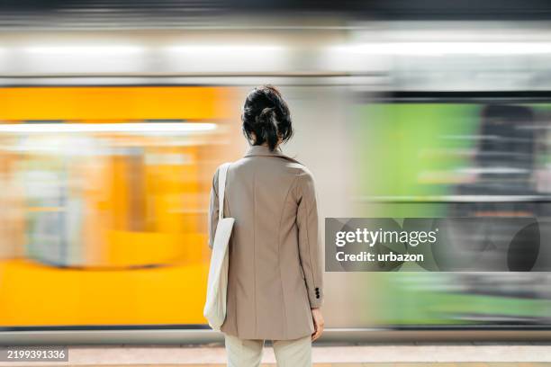 rear-view of a young asian businesswoman waiting for a subway train in sydney in australia - rush hour stock pictures, royalty-free photos & images