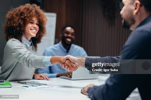 geschäftspartner schütteln sich während eines meetings die hand - rassengleichheit stock-fotos und bilder