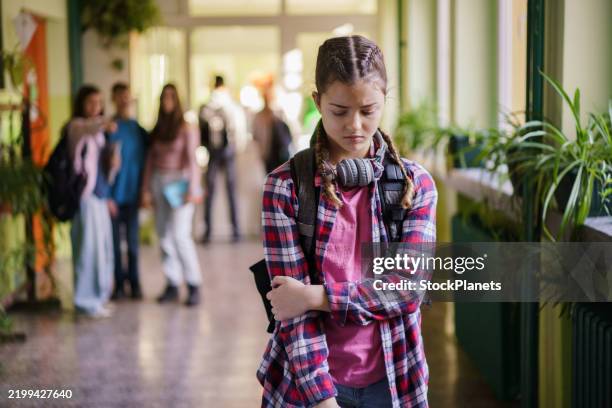 une adolescente triste marche dans le couloir de l’école pendant que les intimidateurs la taquinent - tyranniser photos et images de collection