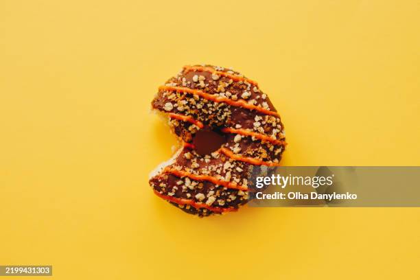 chocolate doughnut with bite on yellow background - missing bite stock pictures, royalty-free photos & images