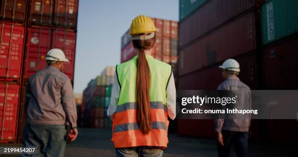 group of logistic workers wearing helmets checking inventory and discussing inspections at commercial transport dock, shipping yard, warehousing, transportation, export, logistics, distribution - confined space stock pictures, royalty-free photos & images