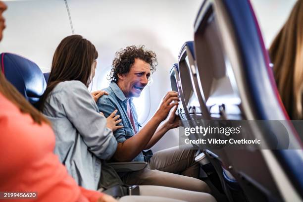 man having panic attack during flight, comforted by his wife - claustrophobia stock pictures, royalty-free photos & images