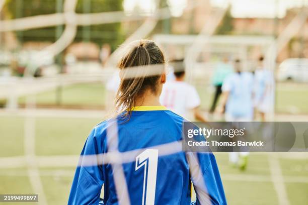 medium shot rear view female soccer goalie in goal during soccer match - womens football stock pictures, royalty-free photos & images