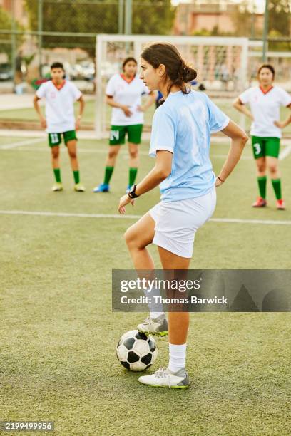 wide shot soccer player standing on urban field with ball under foot - atlete stockfoto's en -beelden