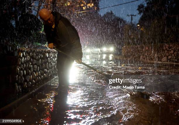 Glenn Lambdin shovels away mud from a mudslide near his home as a powerful atmospheric river storm impacts the region on February 13, 2025 in Sierra...