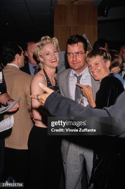 American actress Teri Polo, wearing a halterneck outfit, American actor Charlie Sheen, who wears a fine-check suit, and American actress Lindsay...