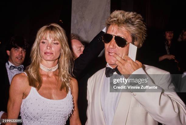 American model Kelly Emberg, wearing a white scooped neck outfit with a multi-strand pearl choker, and her partner, British singer and songwriter Rod...