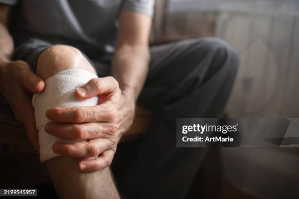 mann mit knieschmerzen zu hause - wundverband stock-fotos und bilder