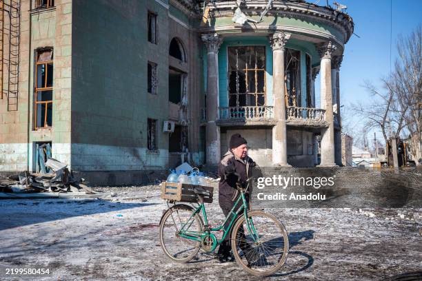 Man walks his bike past the scene of a Russian missile strike on an administrative building in the suburbs of Pokrovsk, Ukraine on 17 February 2025.
