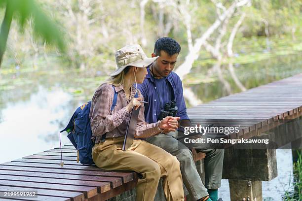 university biology and botany students are exploring and collecting data within a peatland for research using binoculars and taking notes. - naturalist stock pictures, royalty-free photos & images