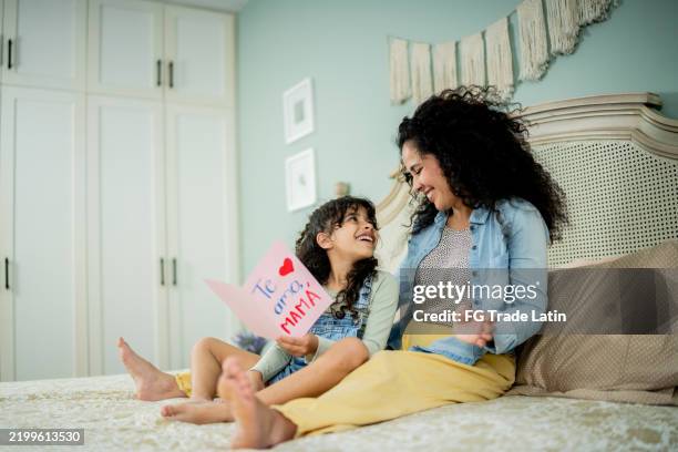 child girl reading letter to mother at home - spanish language stock pictures, royalty-free photos & images