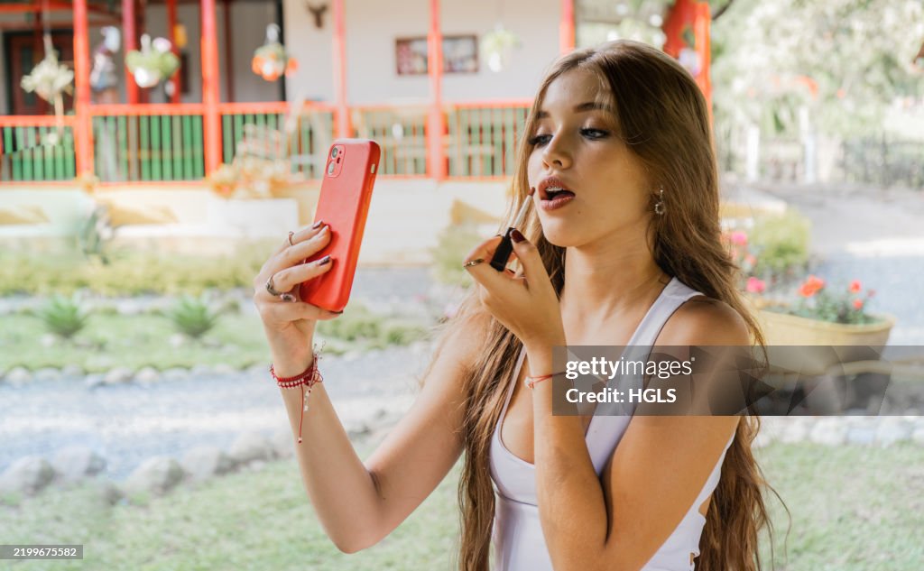 Mädchen im Teenageralter, das Lippenstift im Freien im Wald aufträgt - Stockfoto