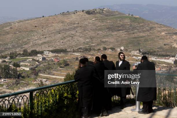 Ultra-Orthodox Jewish men look along the the Lebanese village of Odaisseh as seen from a position on the Israeli side of the border on February 18,...