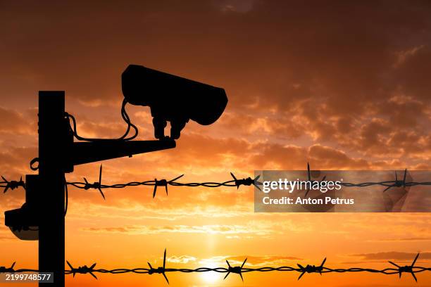 surveillance camera and barbed wire at sunset - international border stock pictures, royalty-free photos & images