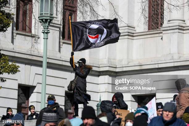 Protester waves an Antifascist Action flag during the demonstration. The "No Kings Day" protest, organized by the 50501 movement on Presidents Day,...