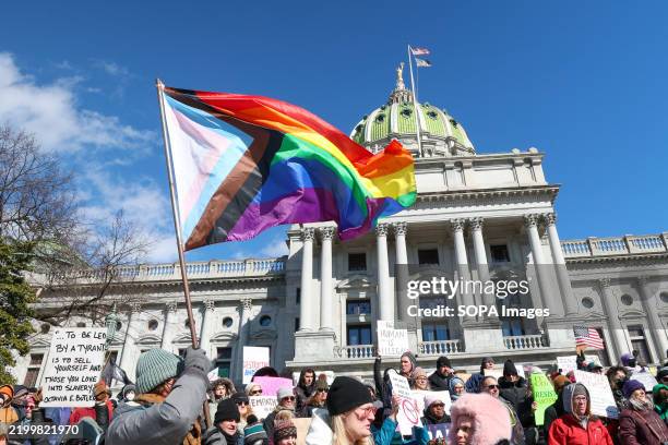 Protester waves a Pride flag during the demonstration outside the Pennsylvania Capitol. The "No Kings Day" protest, organized by the 50501 movement...