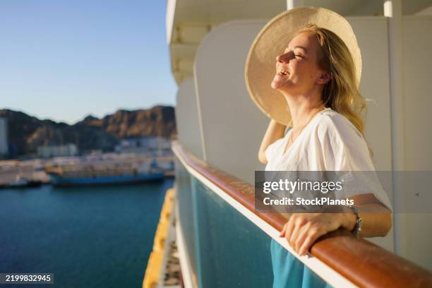 woman whit sun hat standing on a balcony of cruise ship - cruise stockfoto's en -beelden