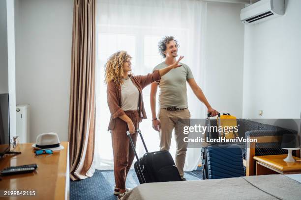 young couple arriving at a hotel room - mirar alrededor fotografías e imágenes de stock